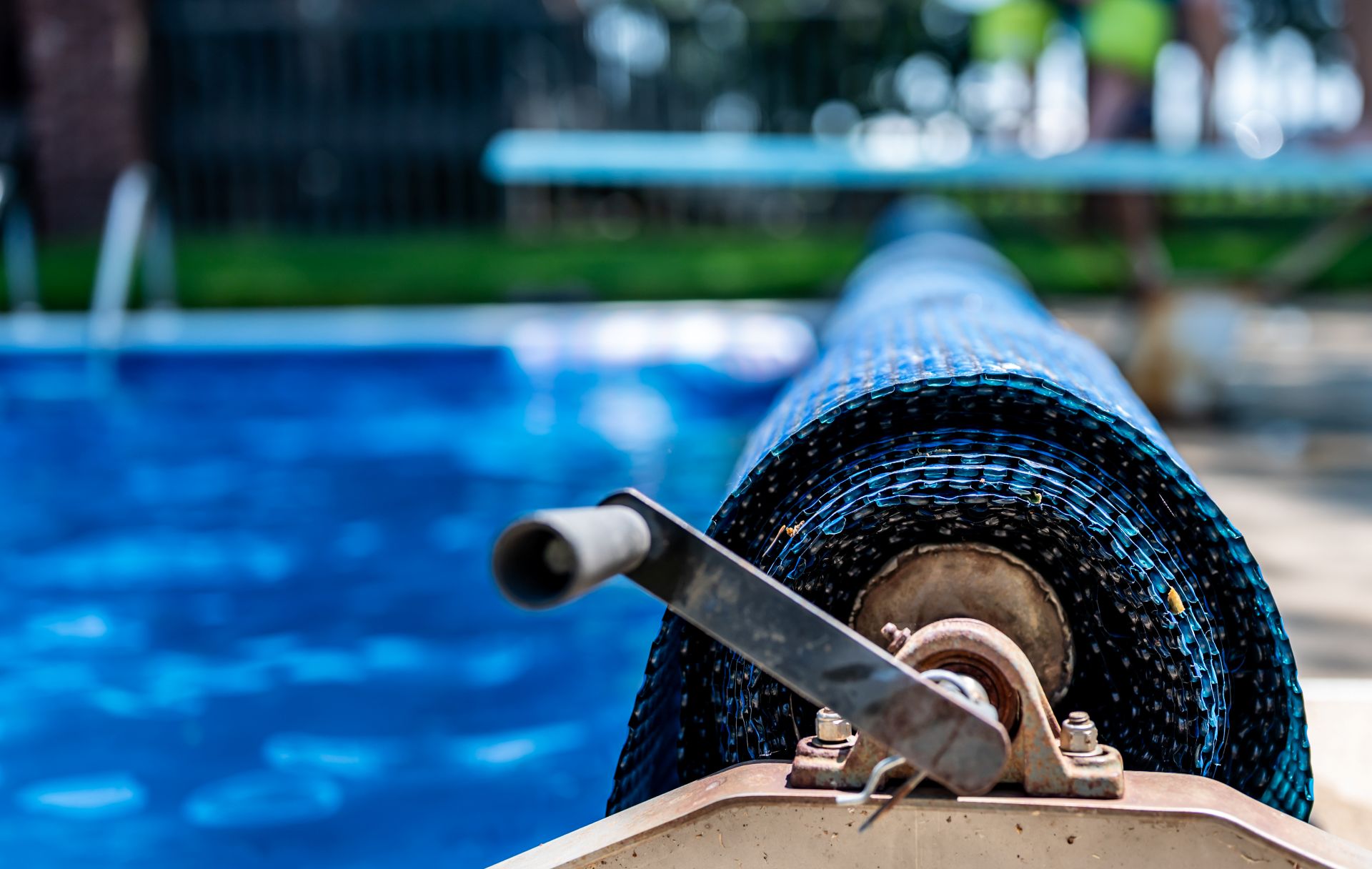 Blaue Poolabdeckung auf Rolle mit Kurbel vor Swimmingpool – Schutz und Komfort fuer den Gartenpool